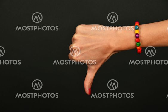 Woman hand shows thumb down gesture over black