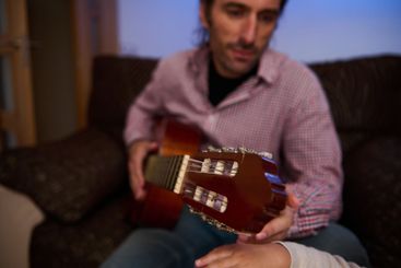 Close-up of a person playing and teaching guitar indoors