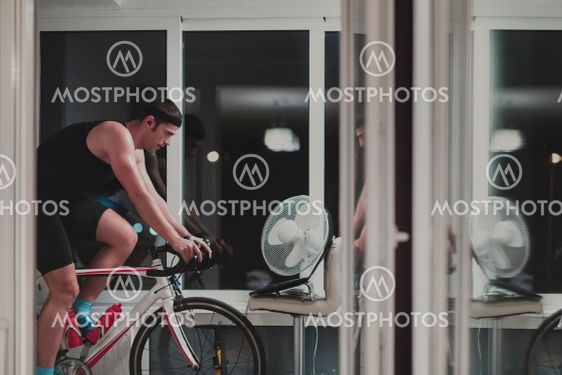 Man cycling on the machine trainer he is exercising in...