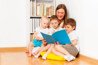 Mother reading book to her three age-diverse kids