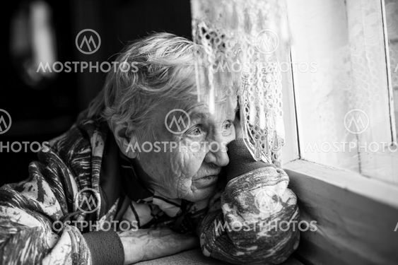 Granny older woman sadly looking out the window.