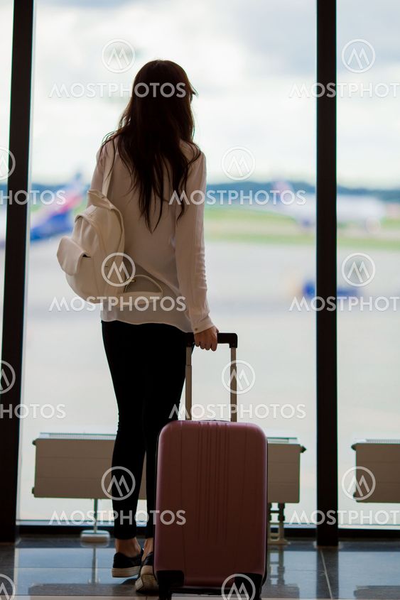 Young woman near window in an airport lounge waiting for...