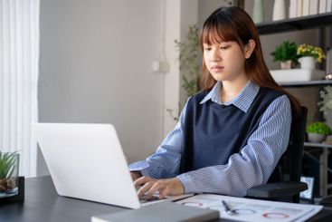 Asian businesswoman using laptop doing documents
