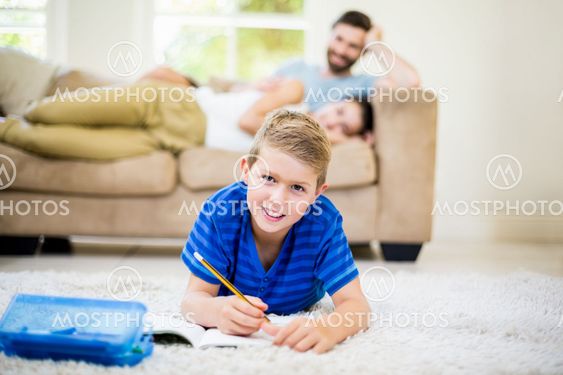 Portrait of boy doing homework in living room