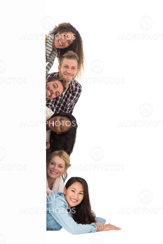 Happy group of young friends peeking from behind a wall