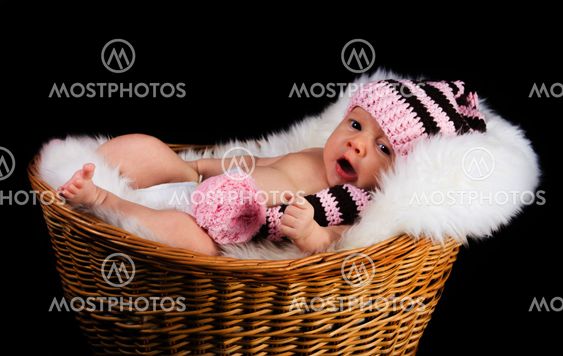 Newborn Child in a wicker basket on a black background.