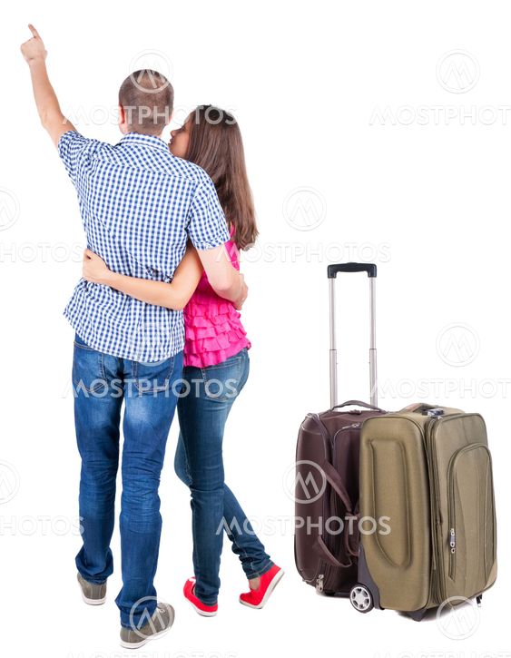 young couple traveling with suitcas and pointing at wal...
