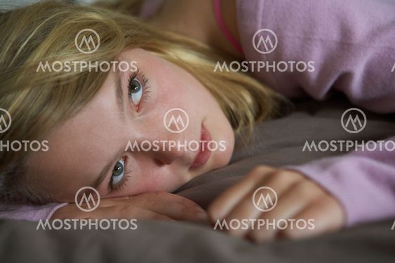 Depressed Teenage Girl Lying In Bedroom