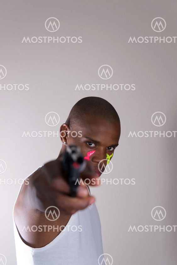 African man in facepaint pointing a gun