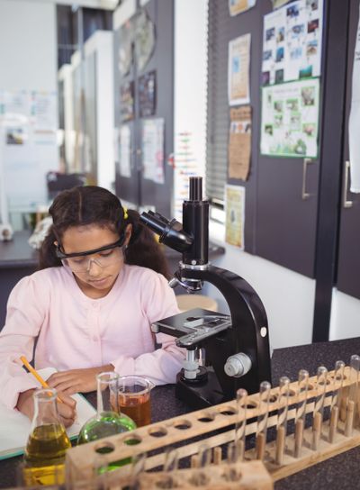 Concentrated elementary student writing in book by...