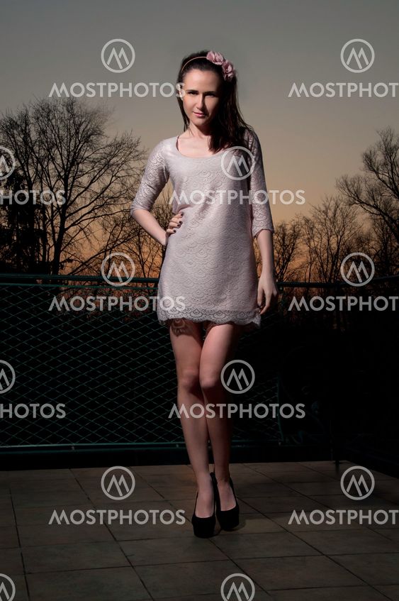 Beautiful woman in light pink dress at sunset
