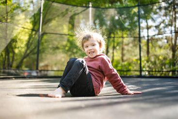 Little boy jumping on a trampoline in a backyard on warm...