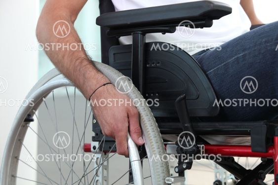 Closeup of a man's hand on the wheel of his wheelchair