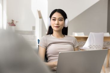 Woman wearing headphones, gazing thoughtfully away on...
