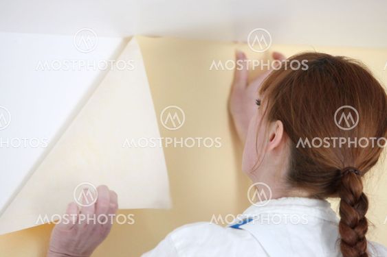 Woman putting up wallpaper