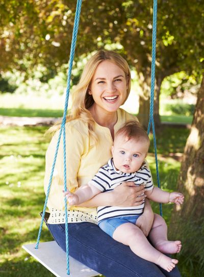 Portrait Of Mother Playing With Baby Son On Garden Swing