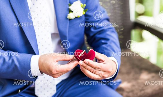 Man's hand holding engagement ring