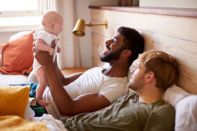 Loving Male Same Sex Couple Cuddling Baby Daughter In...