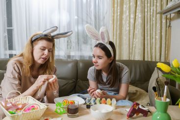 A mother and daughter wearing bunny ears decorating...