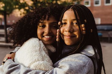 Portrait of smiling female friends embracing each other...