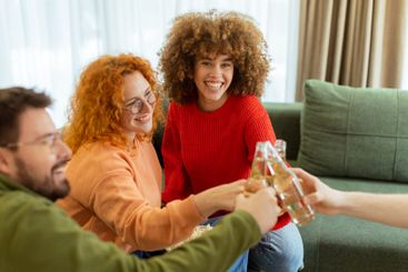 Friends celebrate together in a cozy living room,...