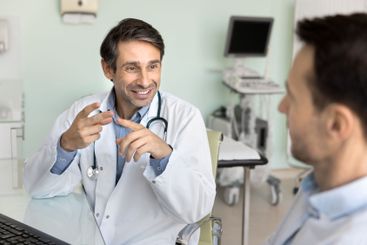 Positive Latin doctor man talking to male patient at...