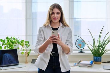 Confident young woman with smartphone in home interior