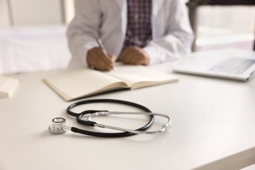 Closeup male physician work with paper documents in...