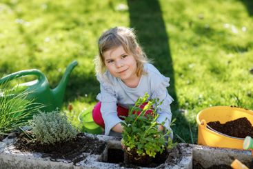 Adorable little toddler girl holding garden shovel with...