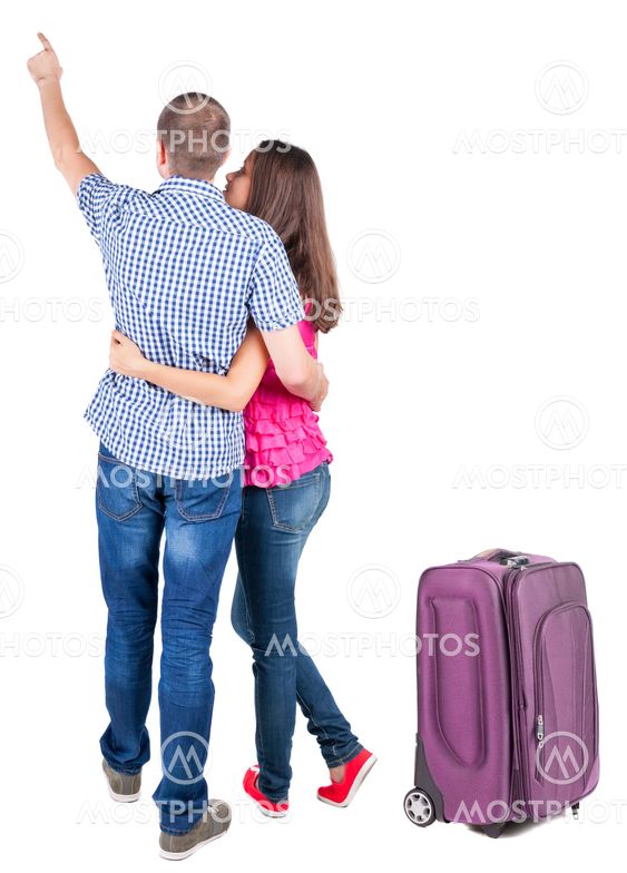 young couple traveling with suitcas and pointing at wal...
