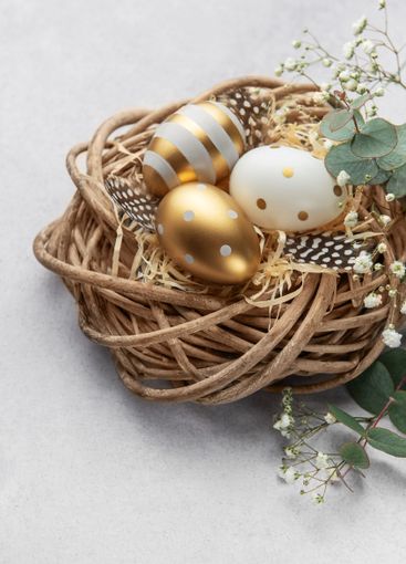Easter eggs resting in a decorative nest with feathers...