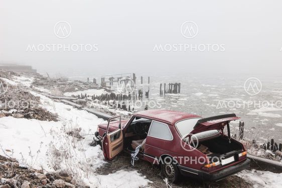 Abandoned car at winter river