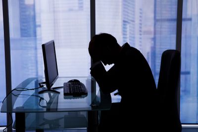 Businessman Sleeping At Computer Desk In Office