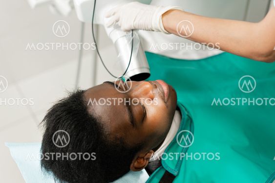 Woman dentist using x ray machine, patient lying on chair...