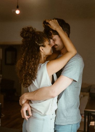 Girlfriend rubbing nose with boyfriend standing at home