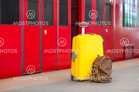 Yellow luggage with passports and brown backpack at train...