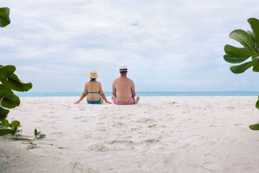 A young married couple is sitting on the sand on the...