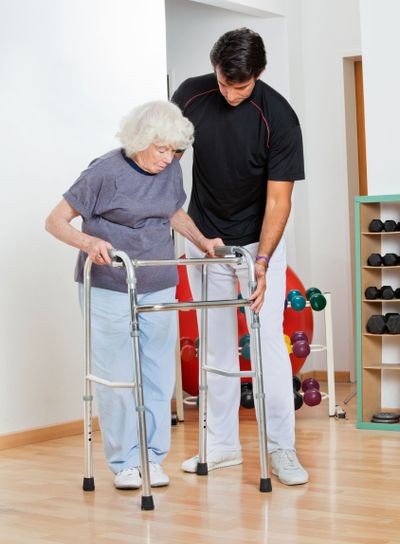Trainer Assisting Senior Woman In Moving