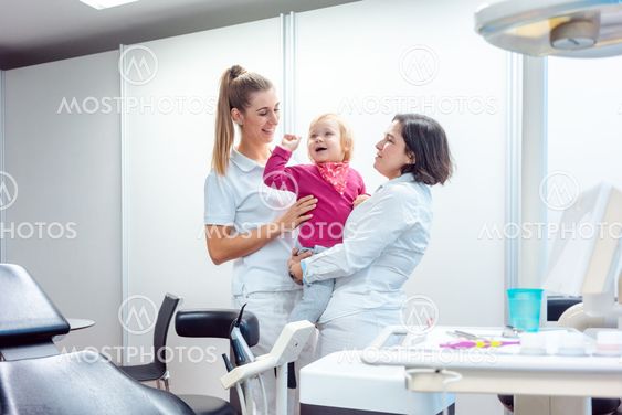 Dentist and her assistant with child in the office