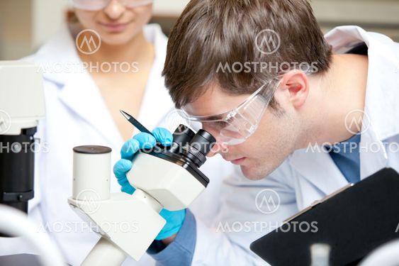 Caucasian male scientist holding pen and clipboard looking throu