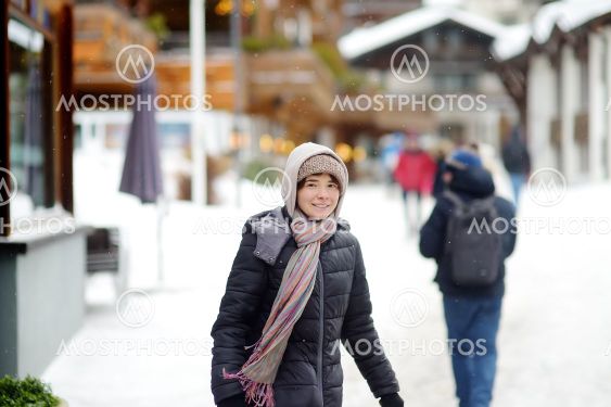 Young woman walking on street of mountain resort town in...