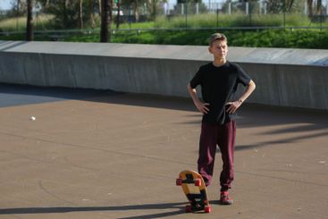 Handsome teenager standing with skateboard. Adolescent...