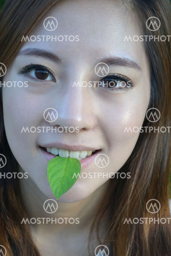 Beautiful young asian women with a leaf in mouth