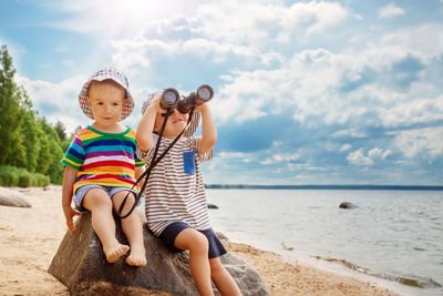 Two children sitting on the stone on the seacoast in...