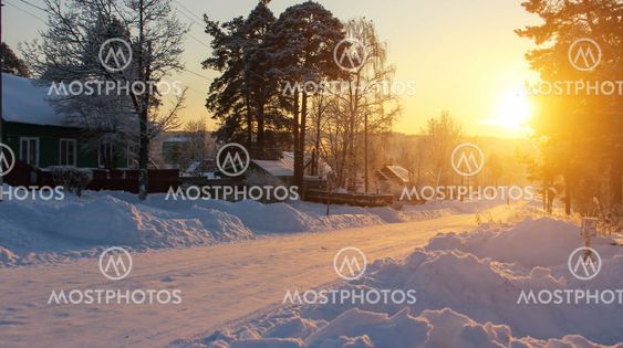 Russian village landscape. Road in the snow during a stunning sunset.