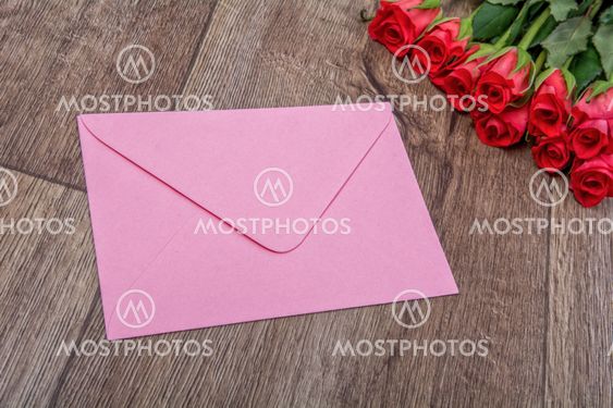 Pink envelope and roses on a wooden background