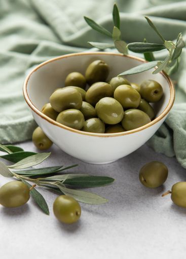 Fresh green olives with olive branches in a bowl,...