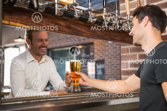 Handsome bar tender giving a pint for a customer