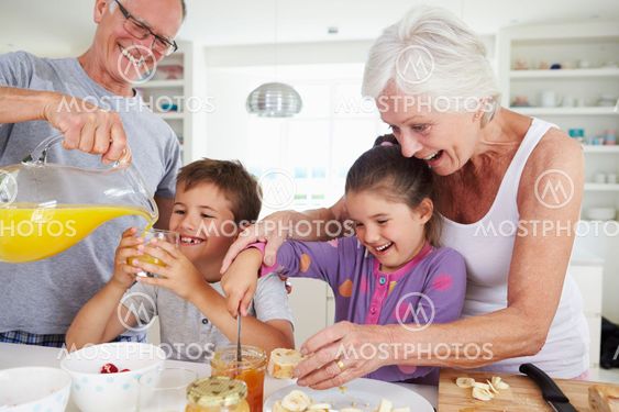 Grandparents With Grandchildren Making Breakfast In Kitchen