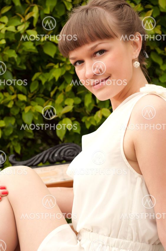 A beautiful woman is sitting on a park bench